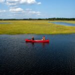 Red canoe on the calm waters of Scarborough Marsh, Maine, during an eco-tour.