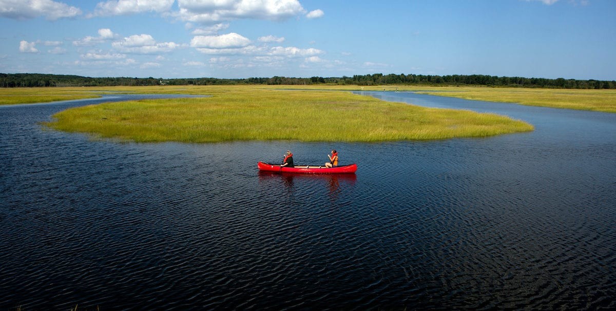 Red canoe on the calm waters of Scarborough Marsh, Maine, during an eco-tour.