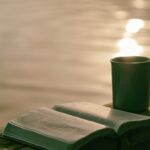 Open Bible and coffee cup by a lakeside, illustrating guided meditation and contemplation of scripture.