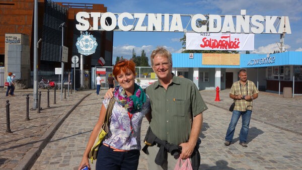 Rick Steves learns about Polish history at the Gdańsk Shipyard from a local guide, highlighting the value of local guides in understanding complex historical events.