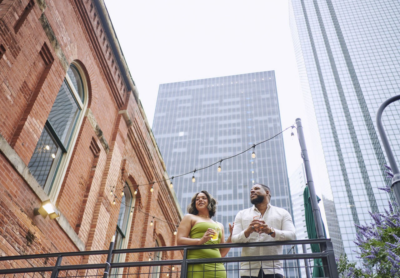 A couple enjoying city views from their balcony in Dallas, complete with cafe lighting for a cozy atmosphere.