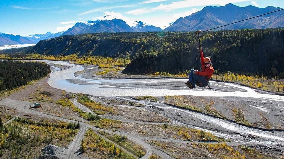 A person is ziplining over a valley in Alaska, showcasing the Nitro zipline experience with MICA Guides.