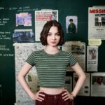 Pip standing with her hands on her hips in front of an evidence board