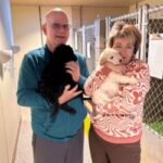 Bob and Ewa with puppies. Bob and Ewa are pictured smiling, surrounded by adorable guide dog puppies.