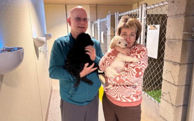 Bob and Ewa with puppies. Bob and Ewa are pictured smiling, surrounded by adorable guide dog puppies.