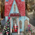 A window display in NYC with various items including a game, books, and candles, suggesting a gift shop setting.