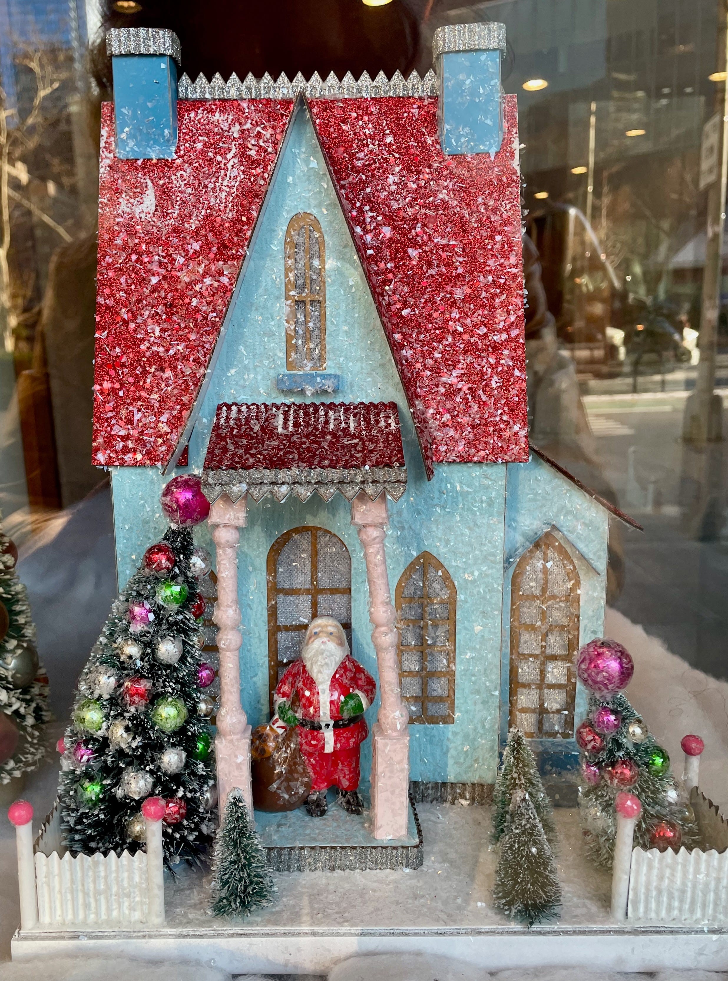 A window display in NYC with various items including a game, books, and candles, suggesting a gift shop setting.