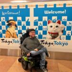 Smiling traveler in wheelchair in front of Japanese temple