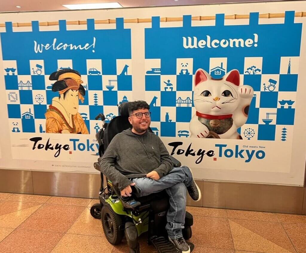 Smiling traveler in wheelchair in front of Japanese temple