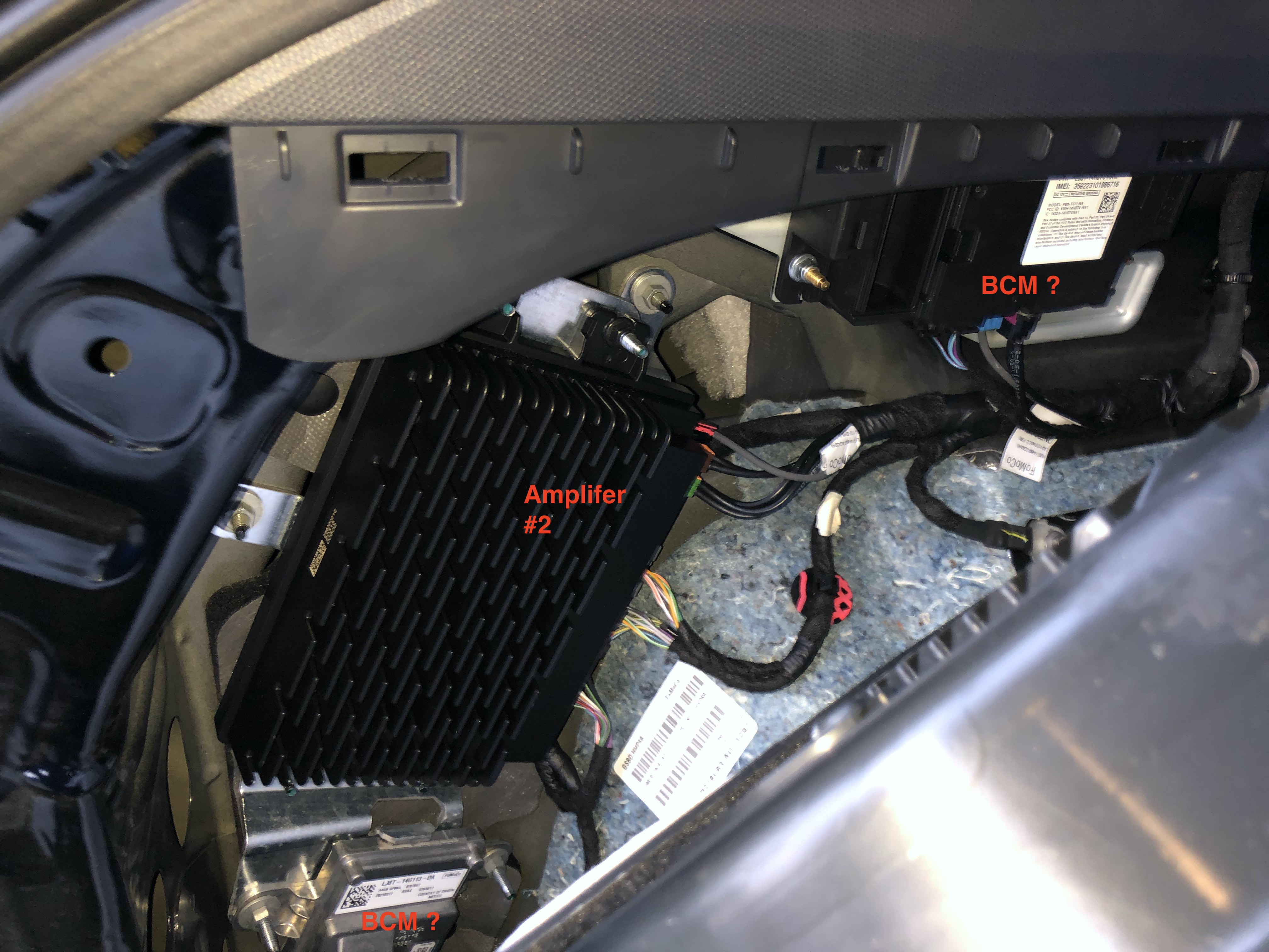 Behind the driver-side panel showing another amplifier and probably a couple of BCMs