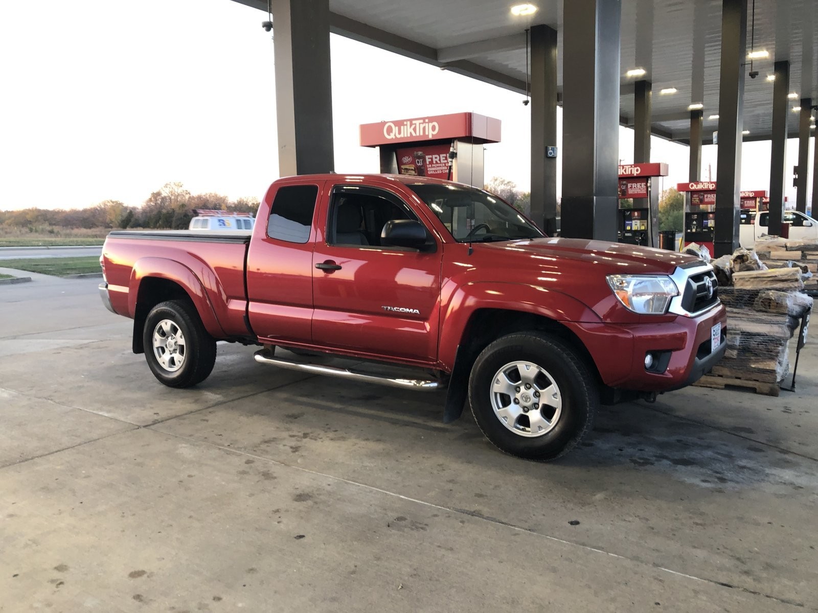 Front view of a red 2015 Toyota Tacoma SR5 access cab, parked outdoors, showcasing its stock appearance upon initial purchase.