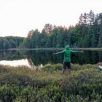 Man stands by lake with bug gear