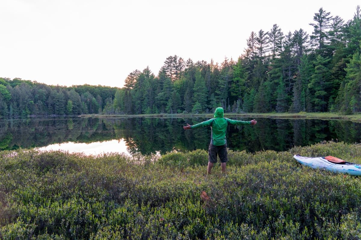 Man stands by lake with bug gear