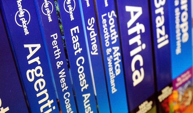 Stack of Lonely Planet travel guide books on a shelf, showcasing various destinations and editions, highlighting the brand's extensive collection of travel resources.