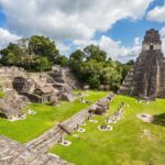 View of majestic mayan ruins with green grass and trees at Tikal National Park in Guatemala near the border of Belize.