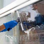 Professional cleaning service worker washes the glass of the windows