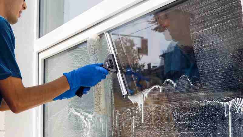 Professional cleaning service worker washes the glass of the windows