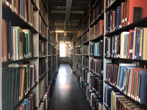 A view down a book-filled aisle in the library stacks