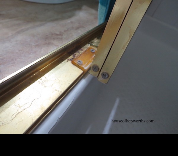 Close-up of a broken shower door bottom guide, highlighting the cracked plastic.