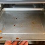 Close-up of food debris and grease splatters inside a Cuisinart Air Fryer Toaster Oven, highlighting the cleaning challenge