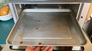 Close-up of food debris and grease splatters inside a Cuisinart Air Fryer Toaster Oven, highlighting the cleaning challenge