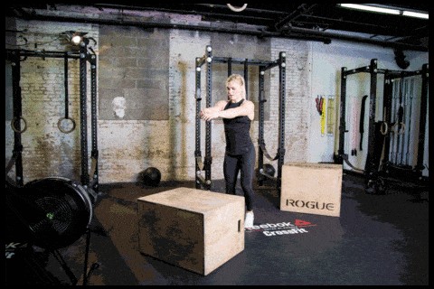 A person performing a box jump during a CrossFit workout, demonstrating a scalable exercise suitable for various fitness levels